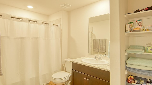 bathroom featuring vanity, walk in shower, and toilet