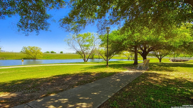 surrounding community with a water view and a yard