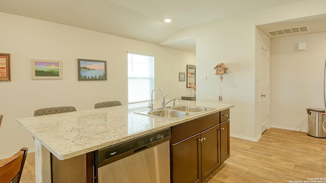 kitchen featuring sink, vaulted ceiling, stainless steel dishwasher, an island with sink, and light hardwood / wood-style floors