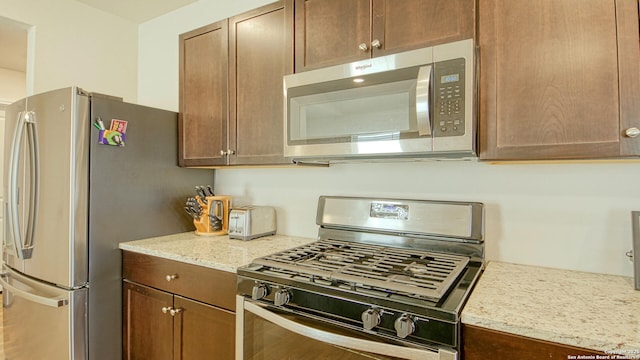 kitchen with stainless steel appliances and light stone counters