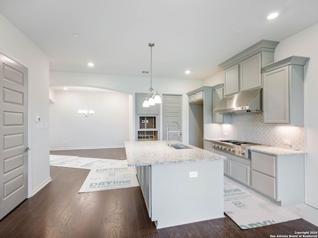 kitchen featuring pendant lighting, sink, light stone counters, stainless steel gas cooktop, and a center island with sink