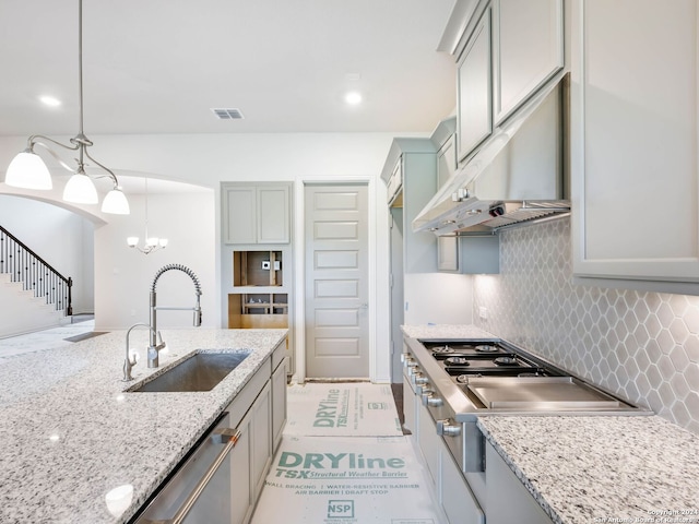 kitchen featuring sink, decorative backsplash, hanging light fixtures, stainless steel dishwasher, and light stone counters