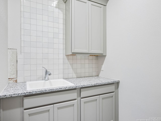 kitchen with tasteful backsplash, sink, and light stone counters