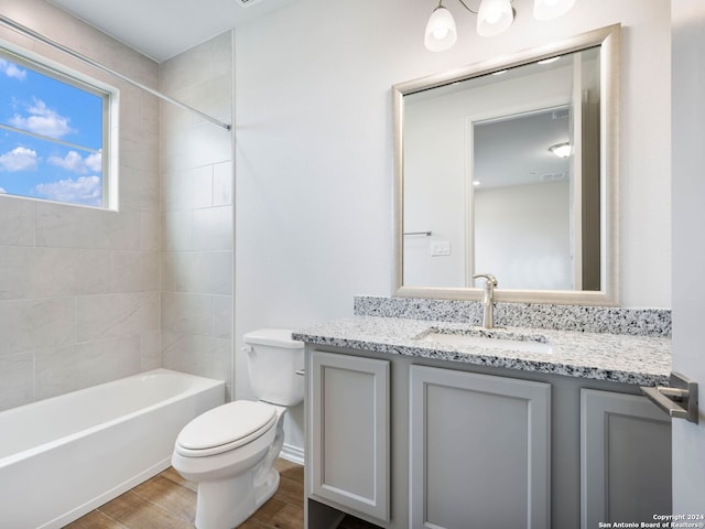 full bathroom with vanity, wood-type flooring, tiled shower / bath, and toilet