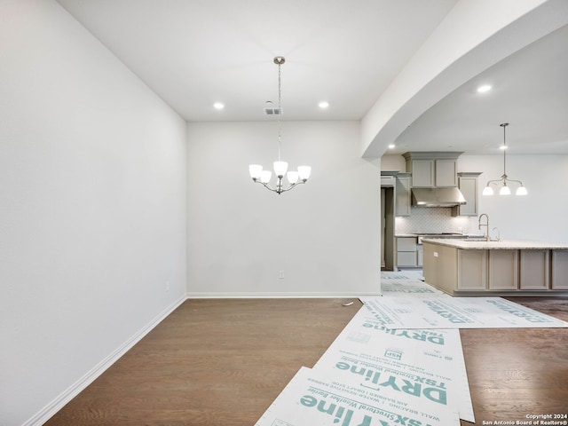 dining space featuring sink, a notable chandelier, and dark wood-type flooring