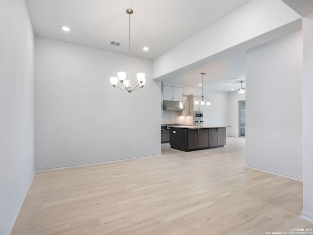 interior space featuring ceiling fan with notable chandelier and light wood-type flooring