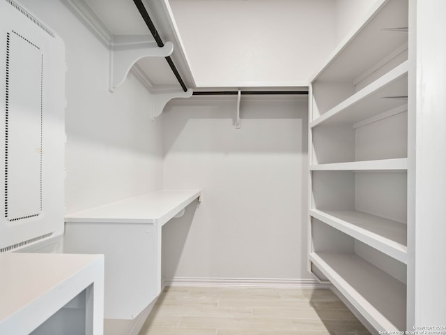 walk in closet with light hardwood / wood-style flooring