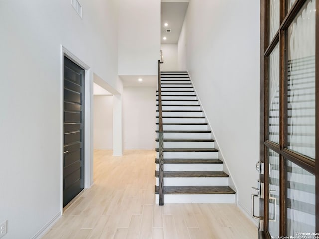 staircase featuring hardwood / wood-style floors and a high ceiling