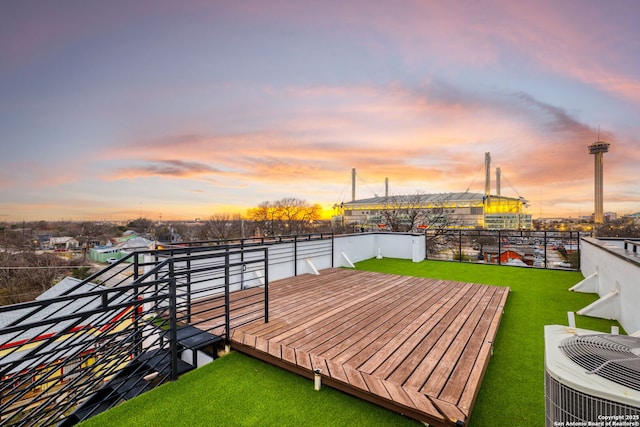 deck at dusk with central AC and a lawn