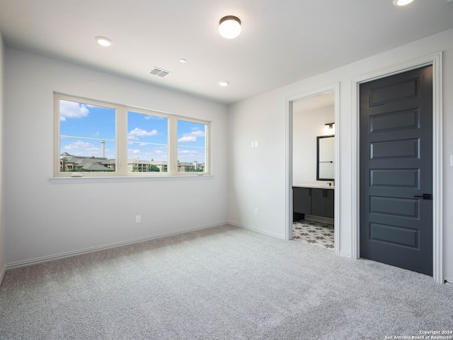 unfurnished bedroom with ensuite bath and light carpet