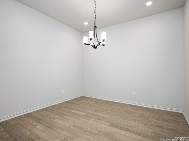 unfurnished room with an inviting chandelier and light hardwood / wood-style flooring