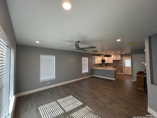 unfurnished living room with dark hardwood / wood-style flooring, sink, and ceiling fan