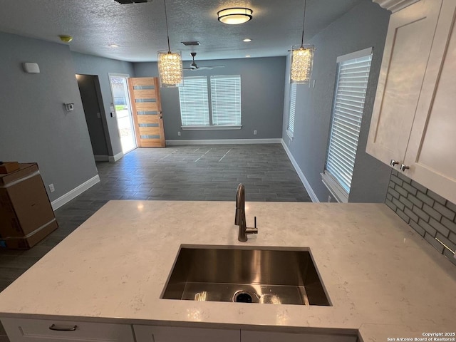 kitchen featuring sink, pendant lighting, white cabinets, and a textured ceiling