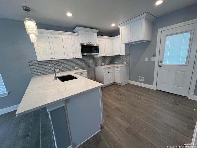 kitchen featuring decorative light fixtures, sink, white cabinets, dark hardwood / wood-style flooring, and decorative backsplash