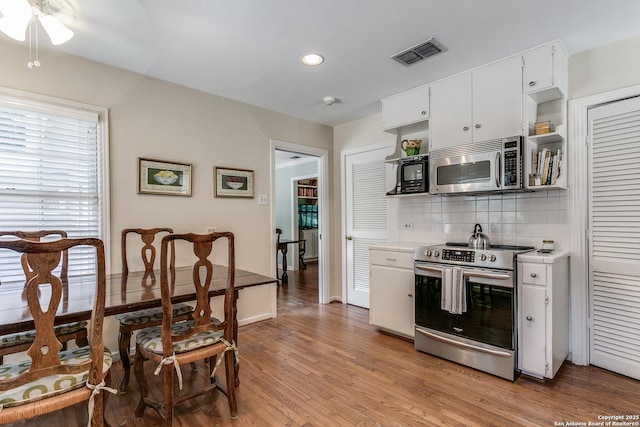 kitchen featuring white cabinetry, stainless steel appliances, decorative backsplash, and light hardwood / wood-style flooring