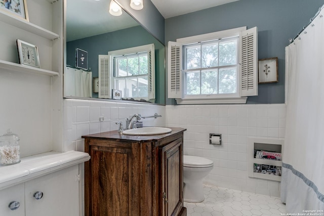 bathroom with tile patterned flooring, vanity, tile walls, and toilet