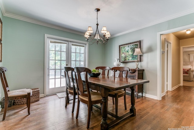 dining room with ornamental molding, hardwood / wood-style floors, and an inviting chandelier