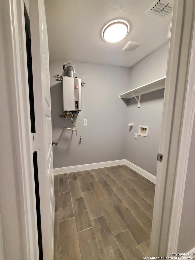 clothes washing area with dark hardwood / wood-style flooring, hookup for a washing machine, and tankless water heater