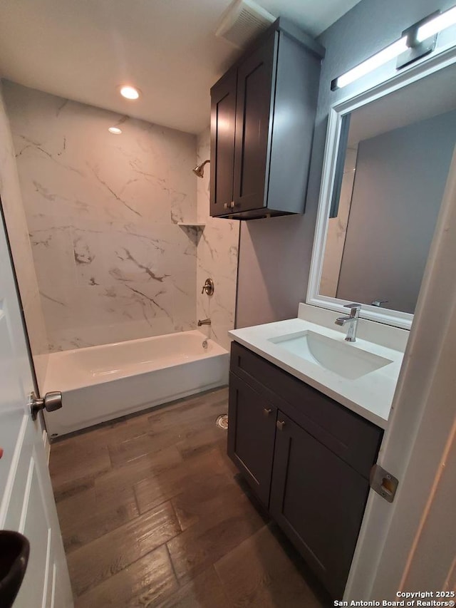 bathroom featuring hardwood / wood-style flooring, vanity, and tiled shower / bath combo