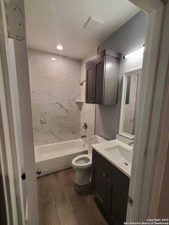 full bathroom with vanity, hardwood / wood-style flooring, toilet, and tiled shower / bath combo