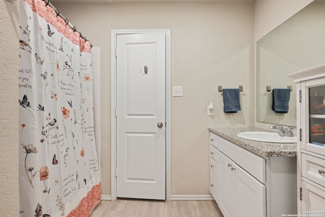 439 Agave Cir, Jourdanton, TX 78026 - bathroom featuring a shower with shower curtain, vanity, and hardwood / wood-style floors