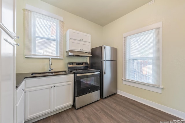 kitchen with plenty of natural light, appliances with stainless steel finishes, sink, and white cabinets