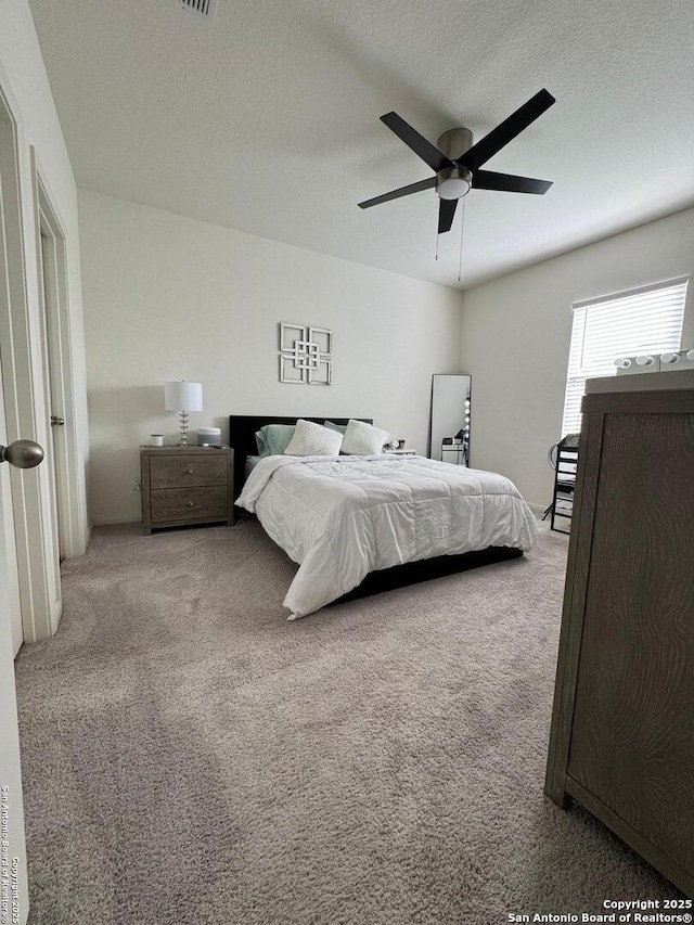 carpeted bedroom with ceiling fan and a textured ceiling