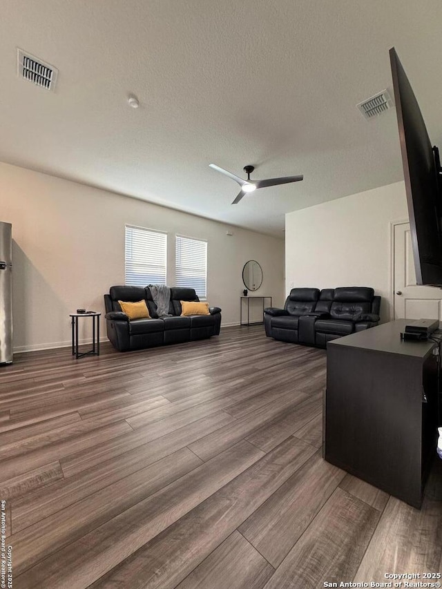 living room featuring hardwood / wood-style flooring, ceiling fan, and a textured ceiling