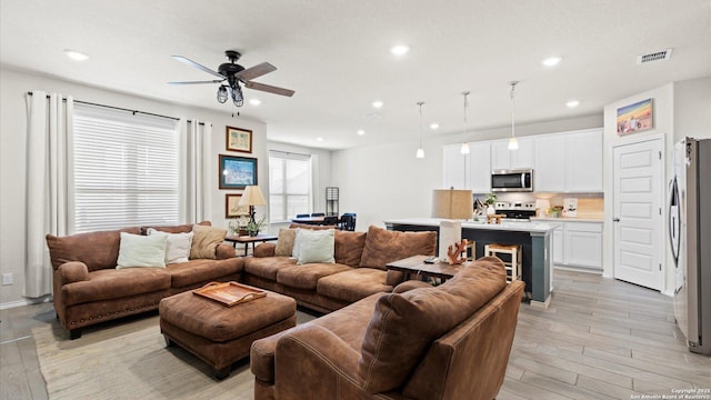 living room with light hardwood / wood-style flooring and ceiling fan