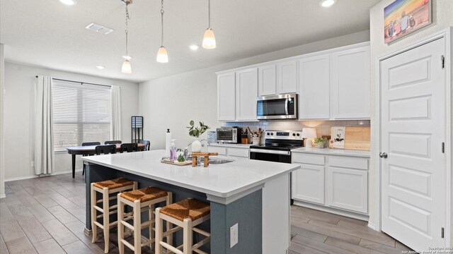 2437 Hiddenbrooke Trce, Seguin, TX 78155 - kitchen featuring a kitchen island with sink, white cabinets, and appliances with stainless steel finishes