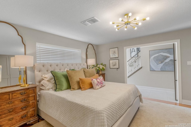 tiled bedroom with an inviting chandelier and a textured ceiling