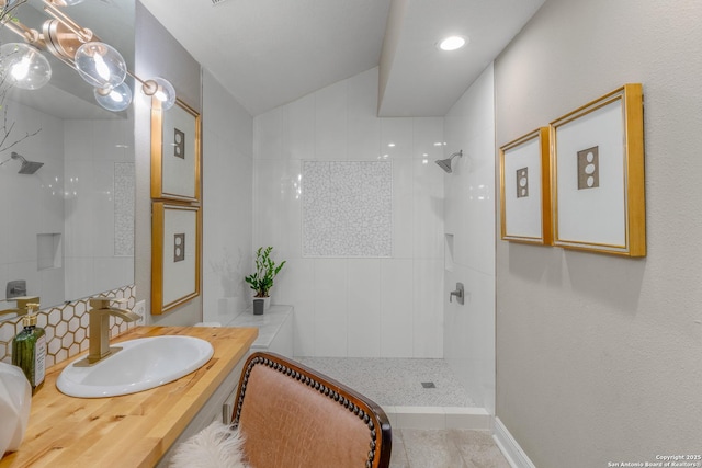 bathroom with vaulted ceiling, tiled shower, backsplash, and vanity