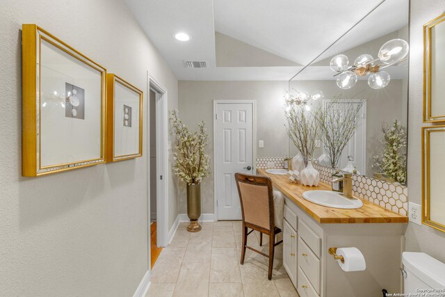 bathroom featuring lofted ceiling, vanity, toilet, and tile patterned flooring