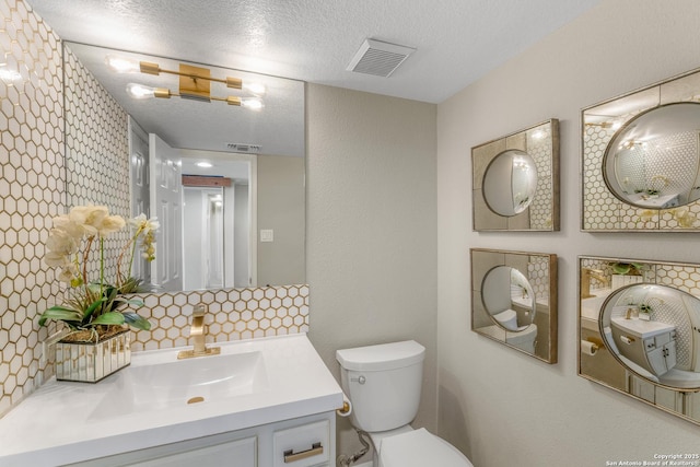 bathroom featuring vanity, decorative backsplash, toilet, and a textured ceiling