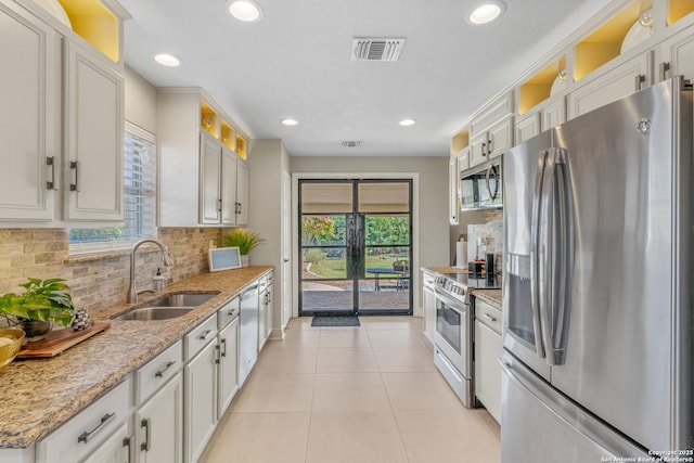 kitchen featuring sink, light tile patterned floors, stainless steel appliances, light stone countertops, and white cabinets