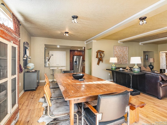 dining space with light hardwood / wood-style floors and a textured ceiling