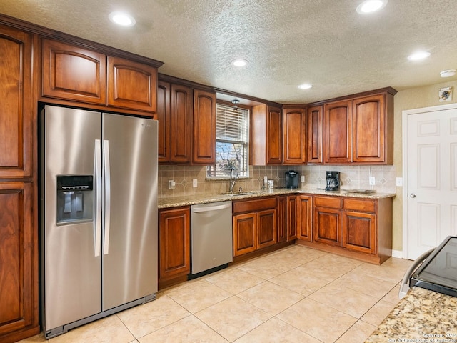 kitchen with light tile patterned flooring, stainless steel appliances, light stone countertops, and backsplash