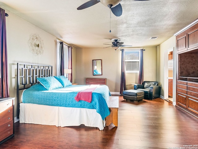 bedroom with ceiling fan, dark wood-type flooring, and a textured ceiling