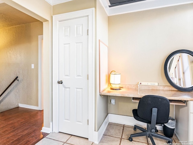 office area featuring light hardwood / wood-style flooring, built in desk, and ornamental molding