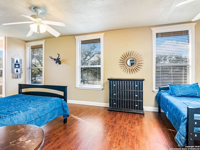 bedroom with dark hardwood / wood-style flooring, ceiling fan, and a textured ceiling