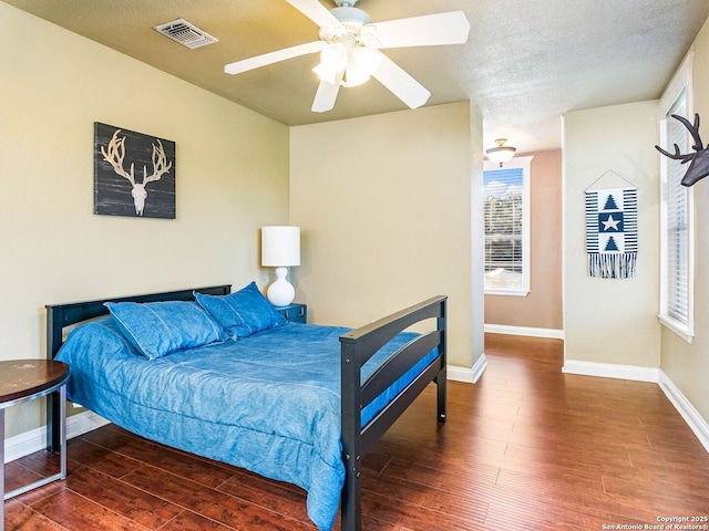 bedroom with ceiling fan, a textured ceiling, and dark hardwood / wood-style flooring