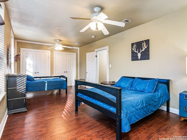 bedroom featuring multiple closets, ceiling fan, dark wood-type flooring, and a textured ceiling