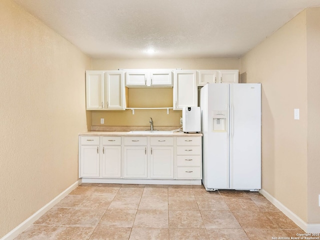 kitchen featuring white cabinetry, sink, light tile patterned floors, and white fridge with ice dispenser