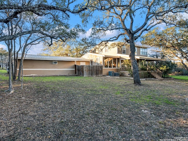 rear view of property with cooling unit, a lawn, and a sunroom