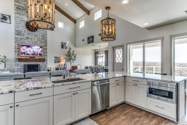 kitchen featuring an inviting chandelier, dark wood-type flooring, a large fireplace, a sink, and dishwasher