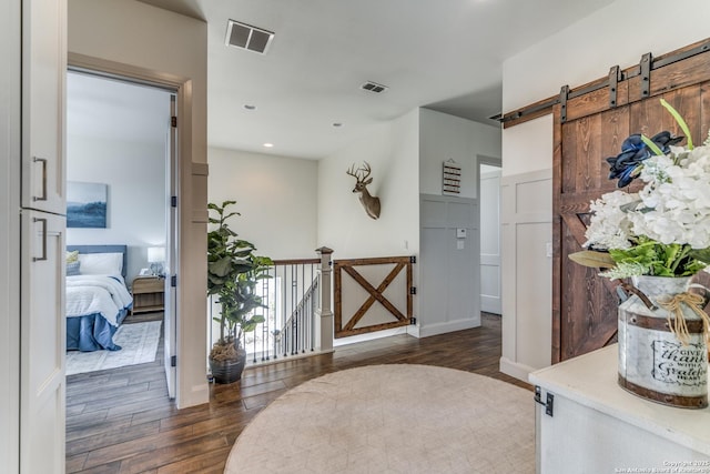 interior space featuring a barn door, wood finished floors, visible vents, and recessed lighting