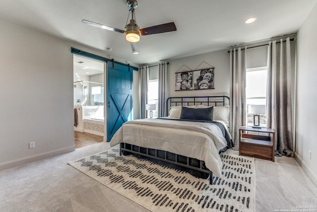 carpeted bedroom with recessed lighting, ensuite bathroom, a barn door, ceiling fan, and baseboards