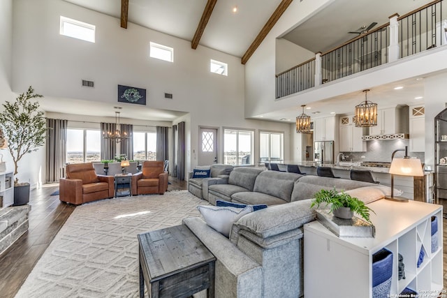 living area with an inviting chandelier, visible vents, dark wood-type flooring, and beamed ceiling