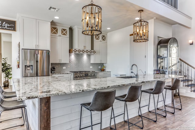 kitchen featuring stainless steel appliances, visible vents, a sink, and a notable chandelier