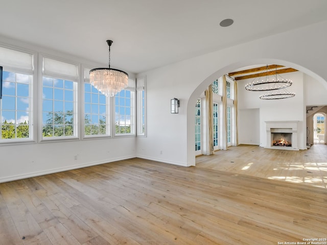 unfurnished dining area with beamed ceiling, light hardwood / wood-style flooring, and a notable chandelier